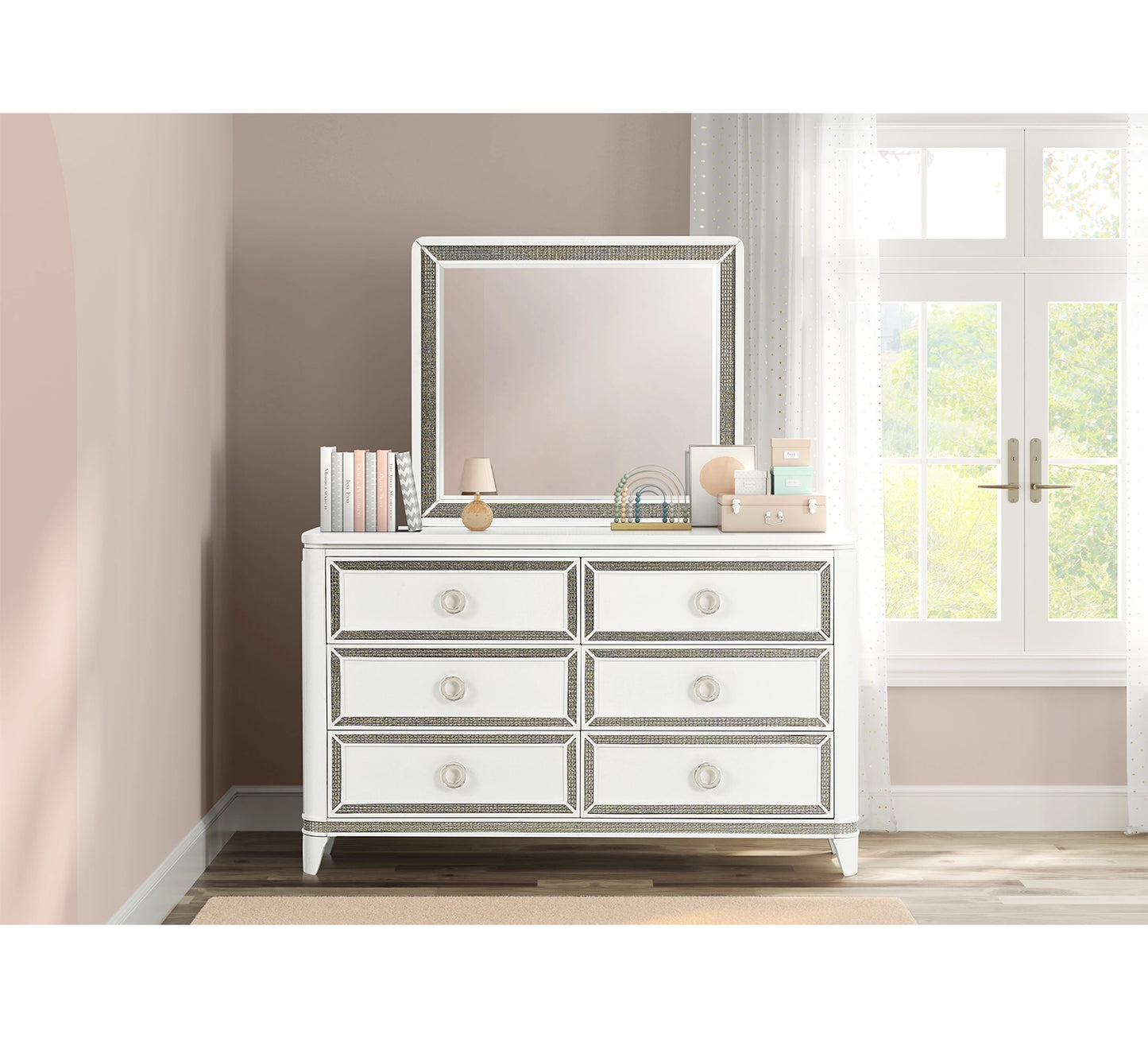 Silver mirrored dresser with decorative items in a room with a window.