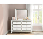 Silver mirrored dresser with decorative items in a room with a window.